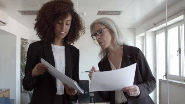 Mulheres de negócios com documentos em pé e falando no escritório — Vídeo de Stock