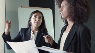 Genç ve güzel iş kadınları raporları ve jestleri tartışıyorlar.