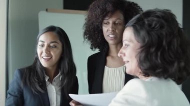 Ciddi iş kadınları ayakta duruyor ve projeyi tartışıyor