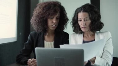 İki içerikli iş kadını birlikte oturuyor ve raporları okuyor.