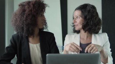 İki ciddi iş kadını birlikte oturup konuşuyor.
