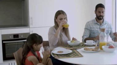 Genç ebeveynler ve küçük çocuk birlikte kahvaltı ediyorlar.