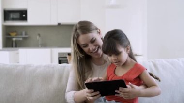 Anne ve küçük tatlı kız tablet üzerinde internet uygulaması kullanıyorlar.