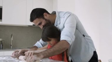 Mutlu baba ve küçük kız birlikte yemek pişiriyorlar.