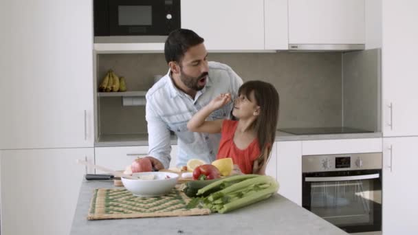 Gelukkig vader en kleine dochter koken salade samen — Stockvideo