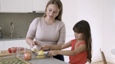 Neşeli anne ve küçük kızı limon sıkıyor.