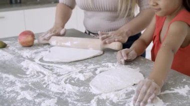 Anne ve küçük kızın elleri birlikte yemek pişiriyor.