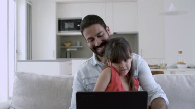 Tatlı küçük kız ve babası video araması için dizüstü bilgisayar kullanıyorlar.