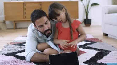 Baba ve küçük kız evde yerde yatıyor.