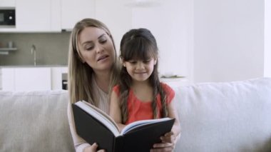 Annesi ve tatlı kızı birlikte kitap okuyorlar.