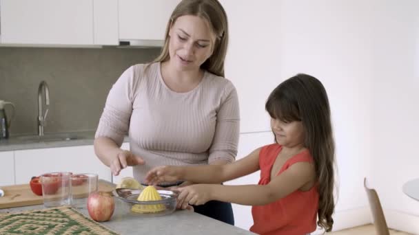 Fröhliche Mutter und kleine Tochter pressen Zitrone — Stockvideo