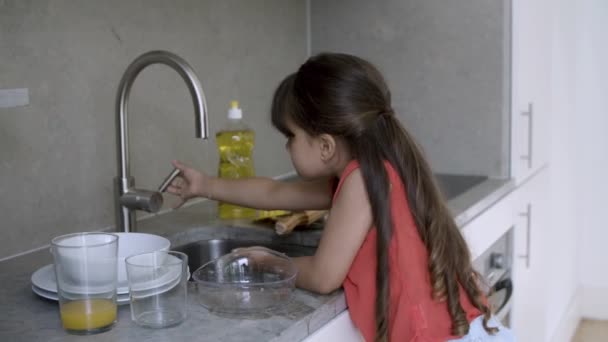 Urocze przedszkola dziewczyna mycie naczynia w kuchni — Wideo stockowe