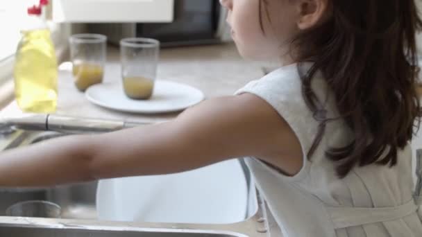 Ernstes kleines Mädchen spült Geschirr selbst — Stockvideo