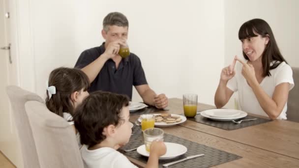 Familia pareja y dos niños bebiendo jugo de naranja fresco — Vídeos de Stock