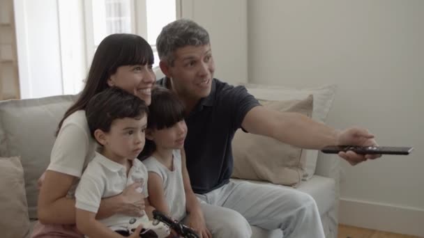 Happy parents couple with two kids watching favorite show — Stock video