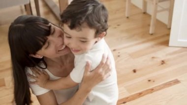 Neşeli anne kucaklıyor, sarılıyor ve küçük tatlı çocuğu öpüyor.