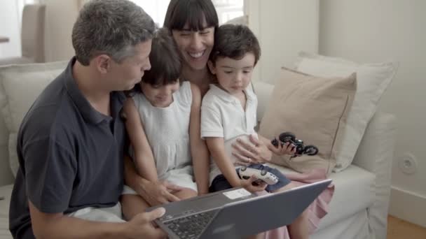 Pais alegres e duas crianças sentadas com laptop no sofá — Vídeo de Stock