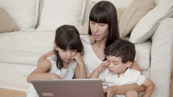 Mom and two kids using learning app on laptop — Stock Video