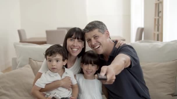 Happy parents couple with two kids watching favorite show — Stock video