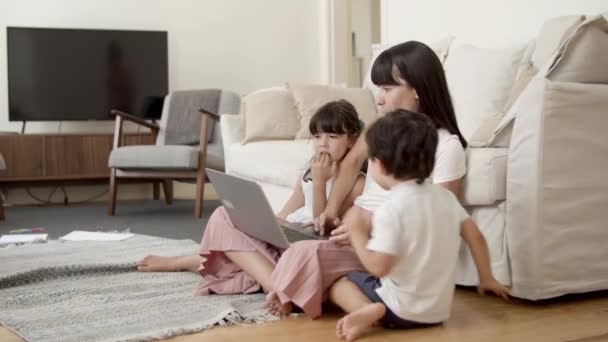 Mama pokazuje zawartość na laptopie dwóm dzieciom — Wideo stockowe