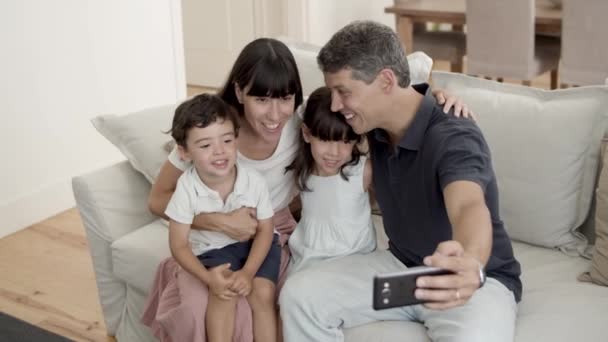 Šťastný pár rodičů se dvěma malými dětmi pózujících pro selfie — Stock video