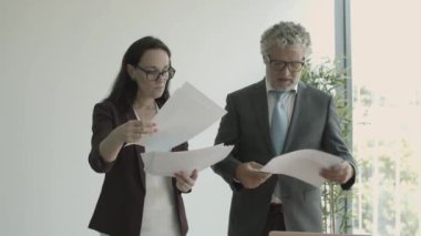 Gri saçlı erkek patron, asistana evrak veriyor.