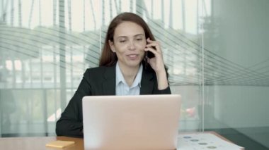 Ofis takımında dizüstü bilgisayar kullanan neşeli bir kadın.