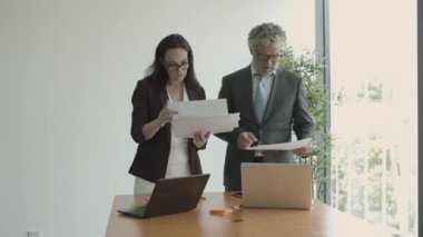 Ciddi bir erkek patron asistanına belge veriyor.