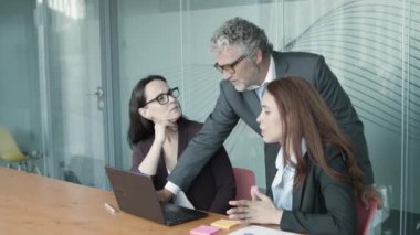 Gri saçlı üst düzey yönetici dizüstü bilgisayardaki sunumu açıklıyor