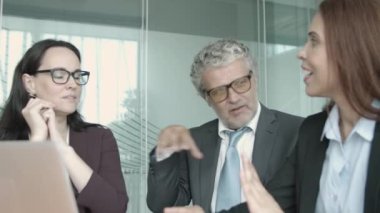Gözlüklü orta yaşlı CEO yöneticilerle konuşuyor.
