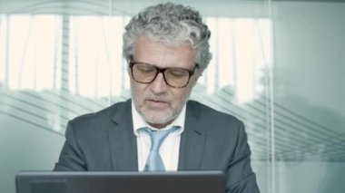 Takım elbise ve gözlük takan olgun bir yönetici.