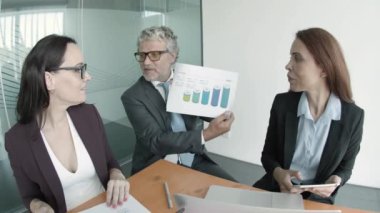 Sakallı orta yaşlı CEO istatistik okuyor ve rapor gösteriyor