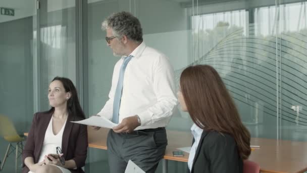 Reifer Geschäftsmann und junge Frauen sitzen und stehen — Stockvideo