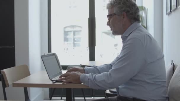 Сосредоточенный взрослый бизнесмен, сидящий на работе — стоковое видео