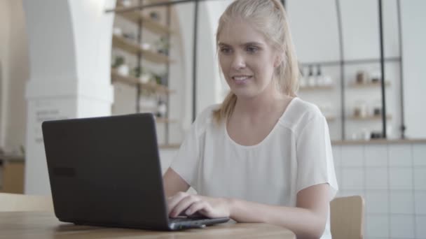 Joven alegre usando el ordenador portátil en el interior co-trabajo — Vídeo de stock