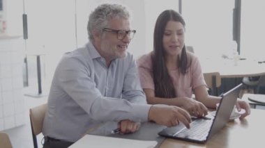 Mutlu girişimciler konuşuyor ve dizüstü bilgisayar kullanıyor.