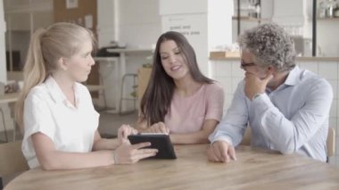 Genç, güzel sarışın kadın tablette bir şey gösteriyor.