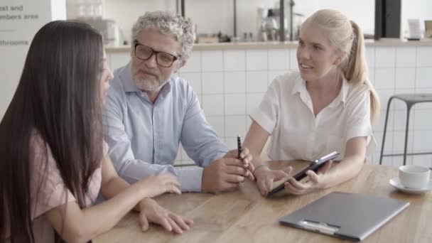 Colegas de conteúdo assistindo tablet tela e sentado à mesa — Vídeo de Stock