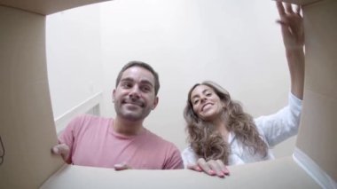 Gülümseyen genç çift karton kutuyu açıp içine bakıyor.