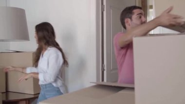 Uzun saçlı bir kadın karton kutuları adama veriyor.