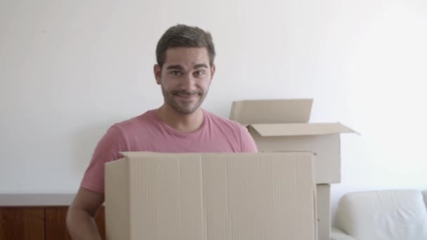 Портрет счастливого молодого человека, держащего картонную коробку и позирующего — стоковое видео