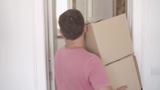 Vista trasera del hombre llevando dos cajas en la cocina — Vídeos de Stock