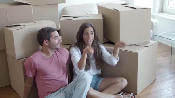 Jeune couple caucasien assis sur le sol près de boîtes en carton — Video