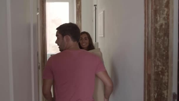 Pareja joven mudándose a una casa nueva y llevando una caja grande juntos — Vídeos de Stock