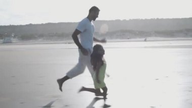 Baba ve küçük kızı sahilde koşuyorlar.