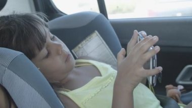 Küçük kız arabada, destek koltuğunda dinleniyor.
