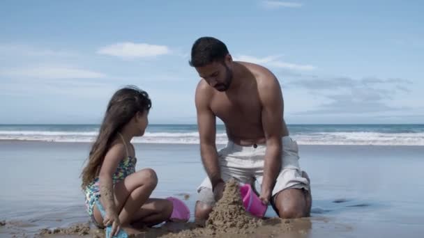 Słodka dziewczynka i jej ojciec budują zamek z piasku — Wideo stockowe