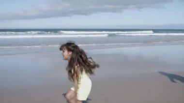 Kumsalda babadan anneye koşan neşeli küçük kız.