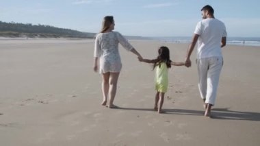 Yazlık kıyafetler giyen genç bir çift ve çocuk.