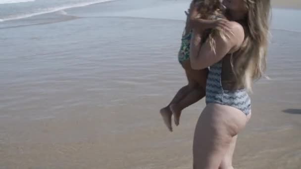 Mama w kostiumie kąpielowym, spacerująca po plaży do wody — Wideo stockowe